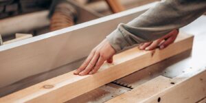carpenter cutting wooden beam using table saw in workshop for custom millwork project