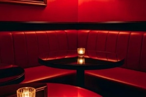 corner booth seating in a dark, luxurious red lounge or bar