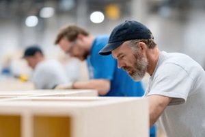 workers crafting wood products in a bright factory setting. Depicts teamwork, skill, and precision