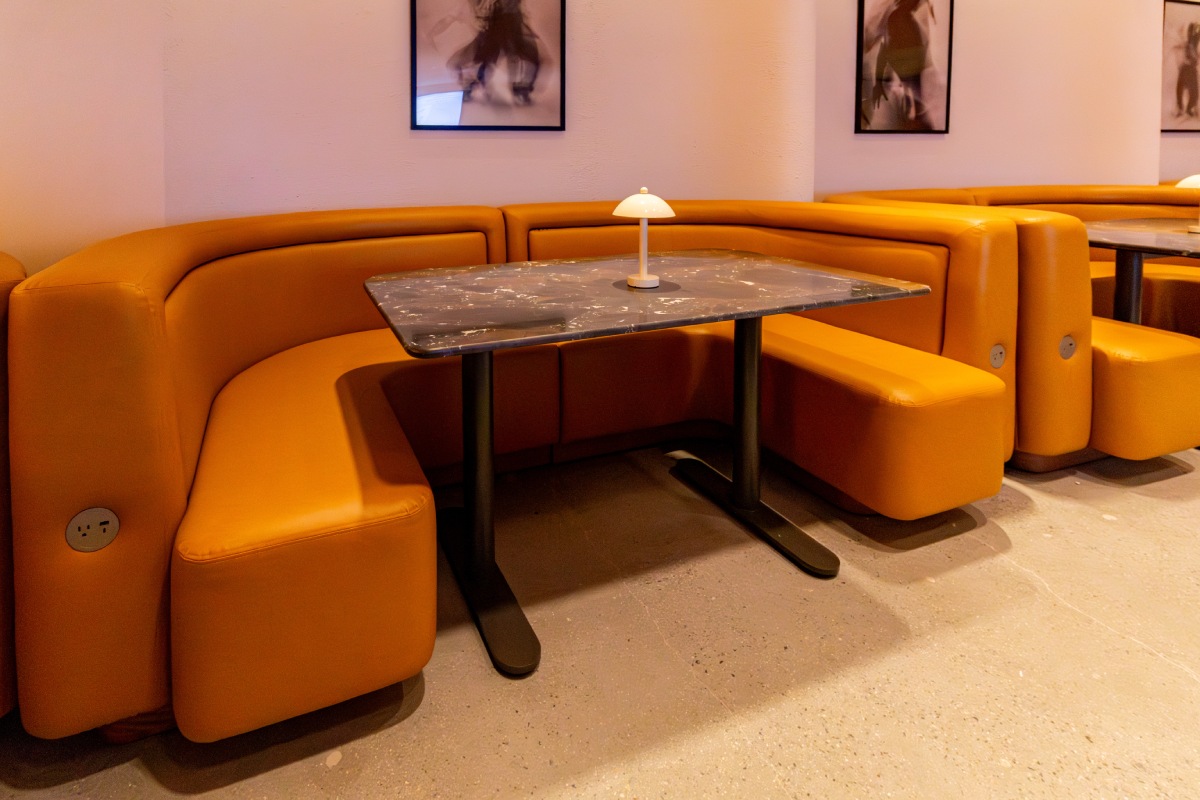 Leather banquette booth seating with stone-top table at Manifest CAW, Washington, DC.