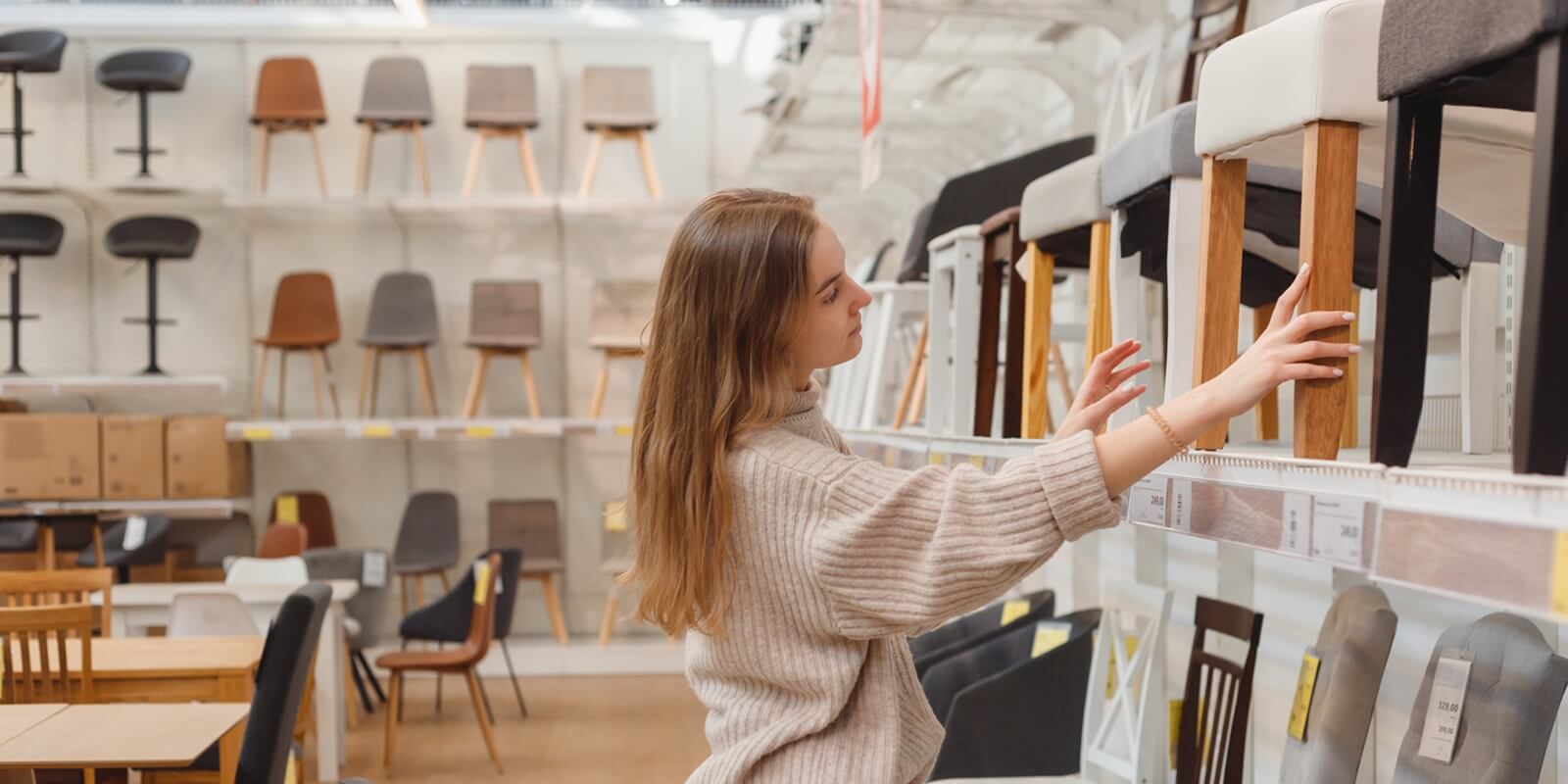 young caucasian woman chooses furniture for her apartment in furniture store